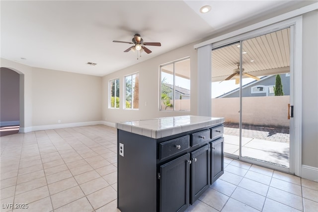 258 Horizon Pointe Cir, Henderson, NV 89012 - kitchen featuring a ceiling fan, tile countertops, light tile patterned floors, arched walkways, and open floor plan
