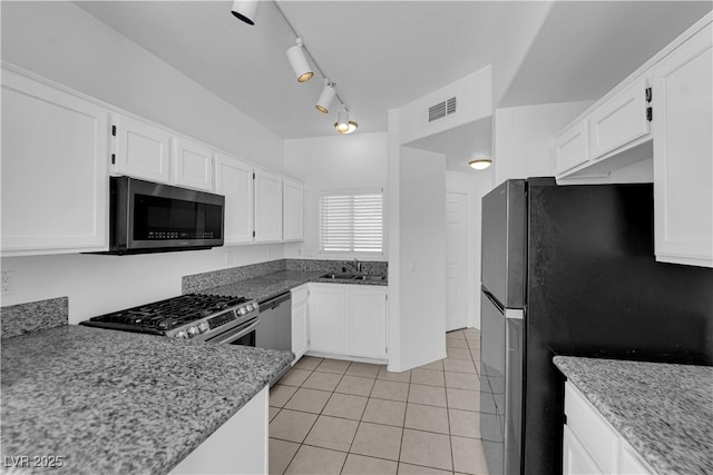 8501 W University Ave Unit 2053, Las Vegas, NV 89147 - kitchen featuring appliances with stainless steel finishes, light tile patterned floors, light stone countertops, and white cabinetry