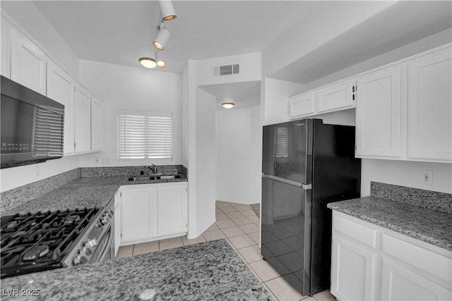 8501 W University Ave Unit 2053, Las Vegas, NV 89147 - kitchen featuring freestanding refrigerator, light stone countertops, white cabinets, and light tile patterned flooring