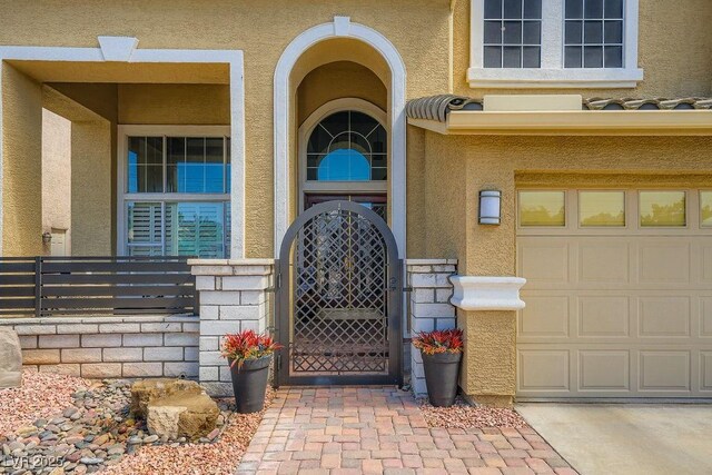 2458 Tour Edition Dr, Henderson, NV 89074 - doorway to property featuring stucco siding, a gate, a garage, and concrete driveway