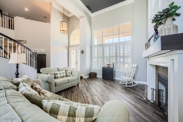 2458 Tour Edition Dr, Henderson, NV 89074 - living area featuring a towering ceiling, crown molding, a fireplace, wood finished floors, and stairs