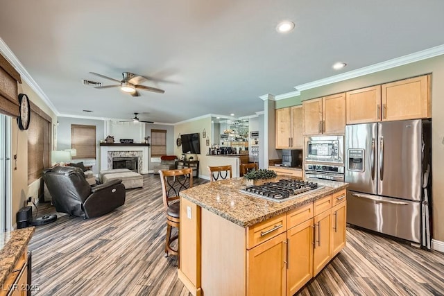 2458 Tour Edition Dr, Henderson, NV 89074 - kitchen with appliances with stainless steel finishes, light brown cabinetry, ceiling fan, wood finished floors, and ornamental molding