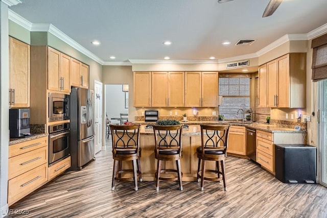 2458 Tour Edition Dr, Henderson, NV 89074 - kitchen featuring stainless steel appliances, light brown cabinetry, a breakfast bar, wood finished floors, and recessed lighting