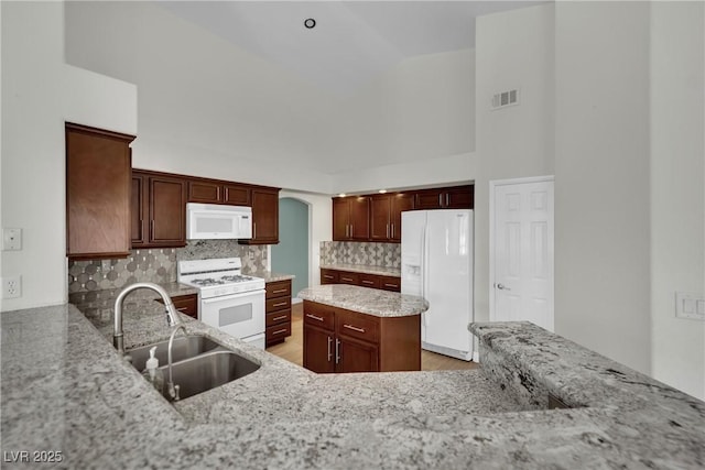 4423 Sophia Way N, Las Vegas, NV 89032 - kitchen featuring white appliances, light stone countertops, decorative backsplash, light wood-type flooring, and arched walkways