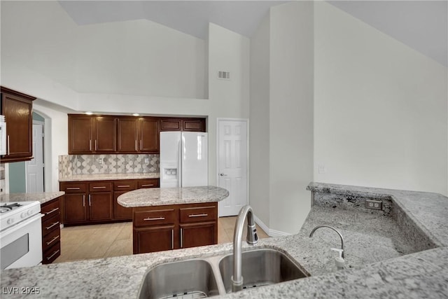 4423 Sophia Way N, Las Vegas, NV 89032 - kitchen featuring white appliances, high vaulted ceiling, decorative backsplash, light stone counters, and a kitchen island