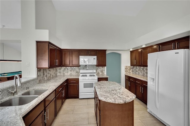 4423 Sophia Way N, Las Vegas, NV 89032 - kitchen with white appliances, decorative backsplash, a center island, light stone countertops, and arched walkways