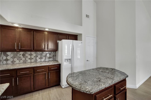 4423 Sophia Way N, Las Vegas, NV 89032 - kitchen featuring white refrigerator with ice dispenser, backsplash, light stone counters, a kitchen island, and light wood-type flooring
