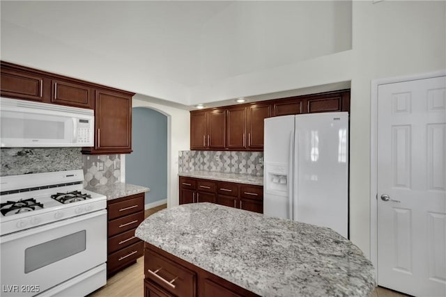 4423 Sophia Way N, Las Vegas, NV 89032 - kitchen with white appliances, tasteful backsplash, light stone countertops, and arched walkways