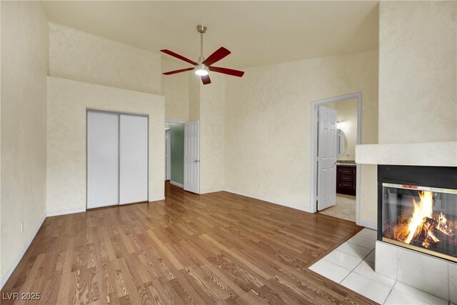 4423 Sophia Way N, Las Vegas, NV 89032 - unfurnished living room with ceiling fan, wood finished floors, a multi sided fireplace, and a towering ceiling