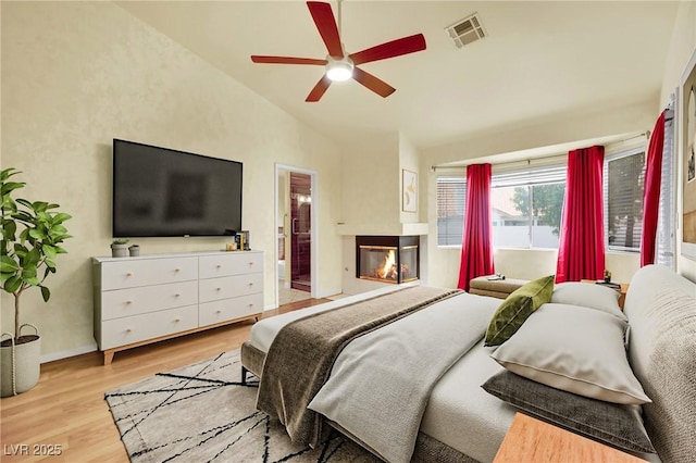 4423 Sophia Way N, Las Vegas, NV 89032 - bedroom with lofted ceiling, a multi sided fireplace, light wood-style flooring, ceiling fan, and connected bathroom