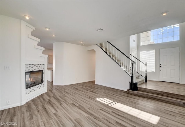 9520 Silver Frost St, Las Vegas, NV 89123 - unfurnished living room featuring stairway, light wood-style flooring, recessed lighting, and a tile fireplace