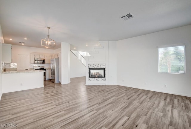 9520 Silver Frost St, Las Vegas, NV 89123 - unfurnished living room featuring light wood-type flooring, recessed lighting, a chandelier, and a tiled fireplace