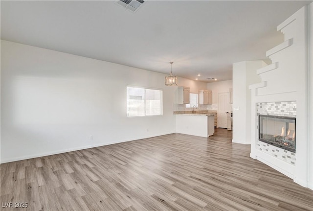 9520 Silver Frost St, Las Vegas, NV 89123 - unfurnished living room with light wood-type flooring, a chandelier, and a fireplace