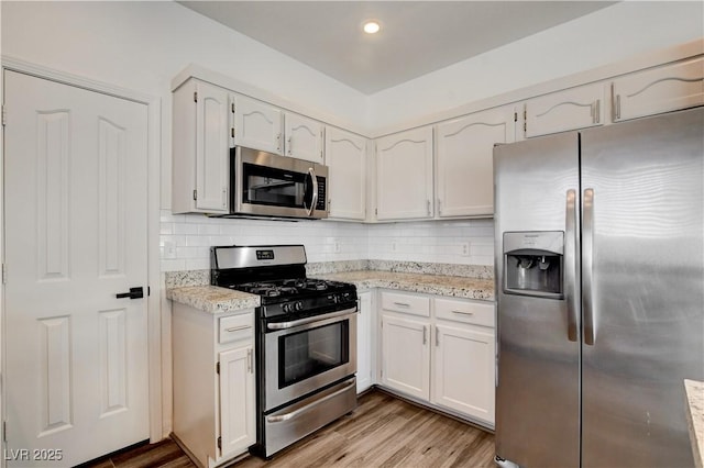 9520 Silver Frost St, Las Vegas, NV 89123 - kitchen with appliances with stainless steel finishes, tasteful backsplash, light wood finished floors, white cabinets, and light stone countertops