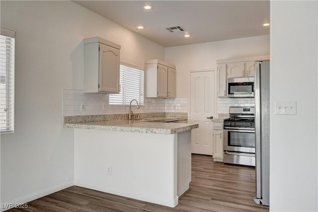 9520 Silver Frost St, Las Vegas, NV 89123 - kitchen featuring appliances with stainless steel finishes, a peninsula, backsplash, wood finished floors, and recessed lighting
