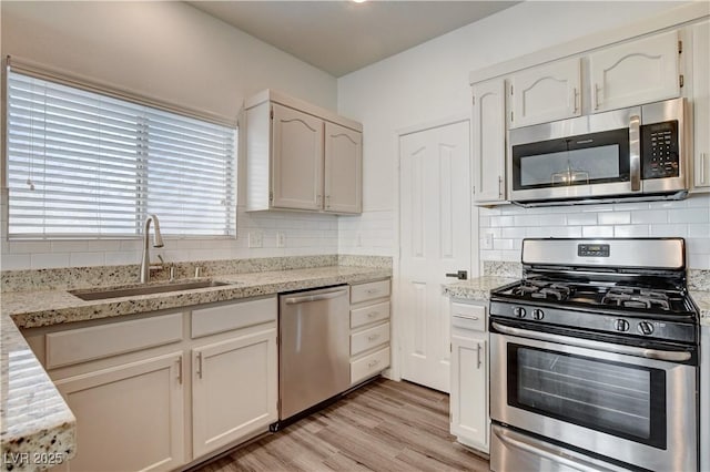 9520 Silver Frost St, Las Vegas, NV 89123 - kitchen with appliances with stainless steel finishes, backsplash, light wood-type flooring, and light stone counters