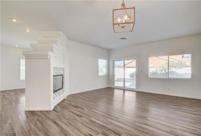 9520 Silver Frost St, Las Vegas, NV 89123 - unfurnished living room featuring light wood-type flooring, a chandelier, a tile fireplace, and recessed lighting