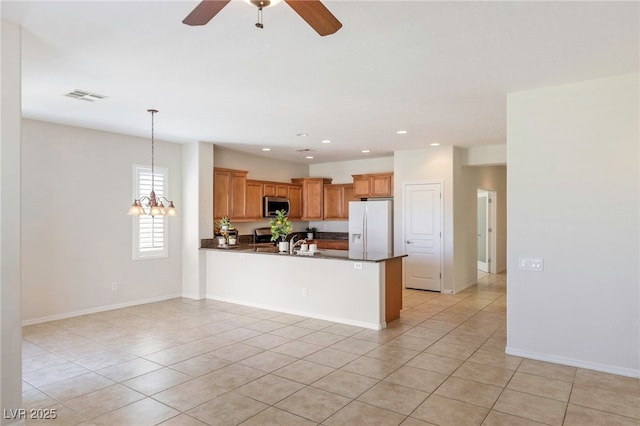 2425 Sky Watcher St, Henderson, NV 89044 - kitchen with stainless steel microwave, white refrigerator with ice dispenser, dark countertops, light tile patterned floors, and recessed lighting