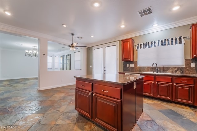 1152 Highbury Grove St, Henderson, NV 89002 - kitchen with crown molding, reddish brown cabinets, stone tile flooring, a kitchen island, and ceiling fan