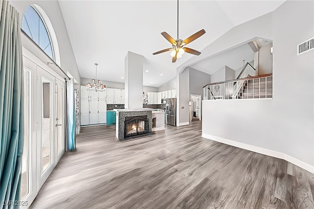 9405 Crosspointe Ave, Las Vegas, NV 89117 - unfurnished living room featuring high vaulted ceiling, ceiling fan, light wood-style floors, stairs, and a chandelier