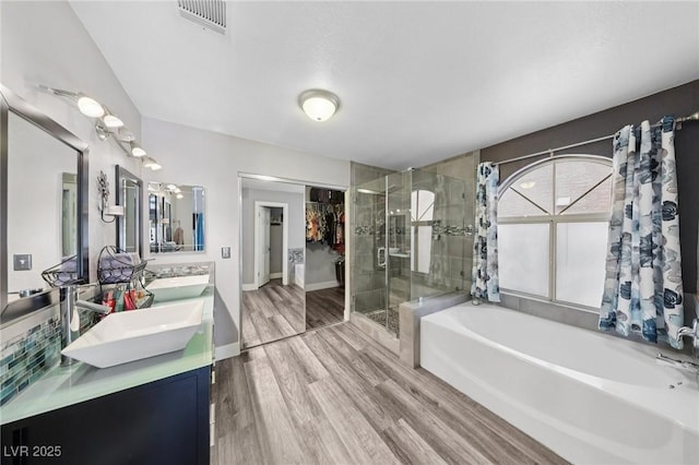 9405 Crosspointe Ave, Las Vegas, NV 89117 - bathroom with a bath, a shower stall, double vanity, wood finished floors, and a spacious closet