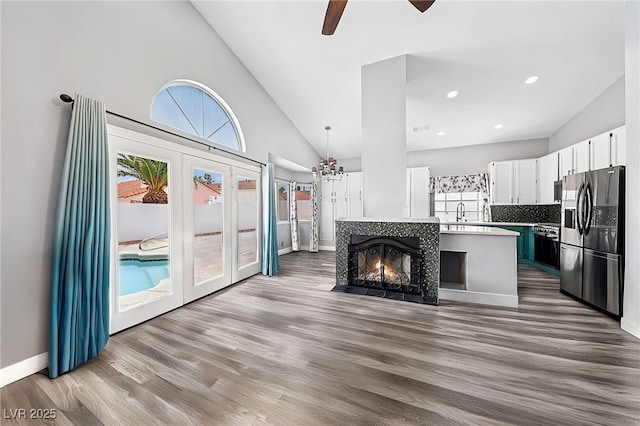 9405 Crosspointe Ave, Las Vegas, NV 89117 - unfurnished living room featuring wood finished floors, a ceiling fan, high vaulted ceiling, french doors, and a chandelier