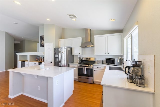 625 Bright Lights Ave, North Las Vegas, NV 89031 - kitchen with appliances with stainless steel finishes, wall chimney exhaust hood, vaulted ceiling, white cabinets, and light wood-style floors