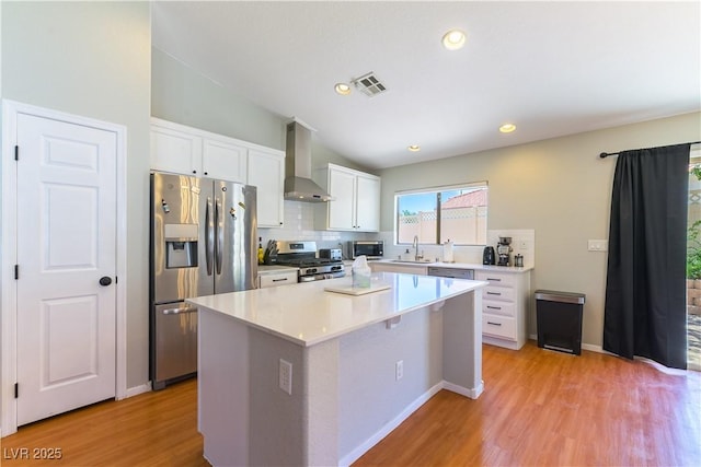 625 Bright Lights Ave, North Las Vegas, NV 89031 - kitchen featuring wall chimney range hood, stainless steel appliances, white cabinets, a kitchen island, and light wood-style floors