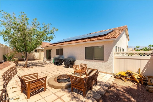 625 Bright Lights Ave, North Las Vegas, NV 89031 - rear view of house with an outdoor fire pit, stucco siding, a fenced backyard, roof mounted solar panels, and a patio