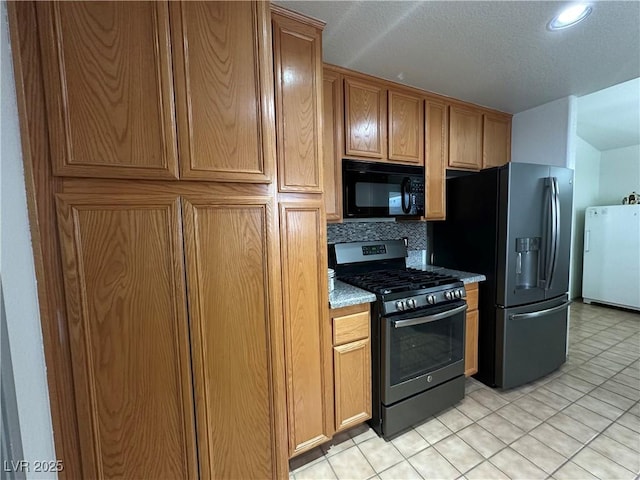 5449 Bugle Way Unit 105, Las Vegas, NV 89108 - kitchen featuring black microwave, gas range oven, freestanding refrigerator, stainless steel fridge, and tasteful backsplash
