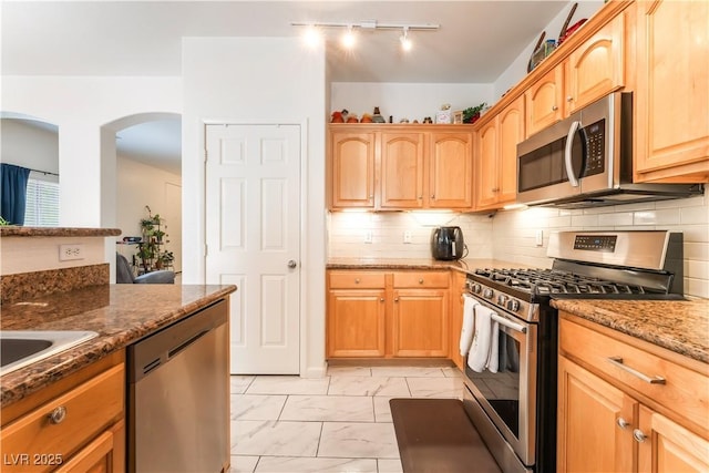 6312 Beige Bluff St Unit 102, North Las Vegas, NV 89081 - kitchen featuring appliances with stainless steel finishes, light marble finish floors, dark stone countertops, track lighting, and tasteful backsplash
