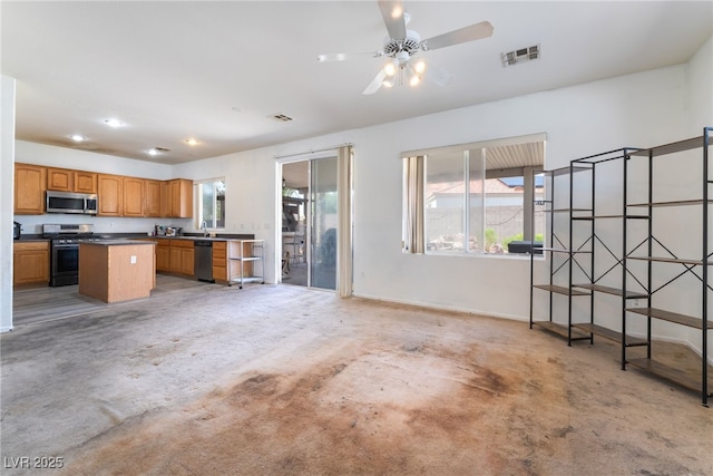 4062 W El Campo Grande Ave, North Las Vegas, NV 89031 - kitchen with appliances with stainless steel finishes, a kitchen island, brown cabinets, dark countertops, and open floor plan