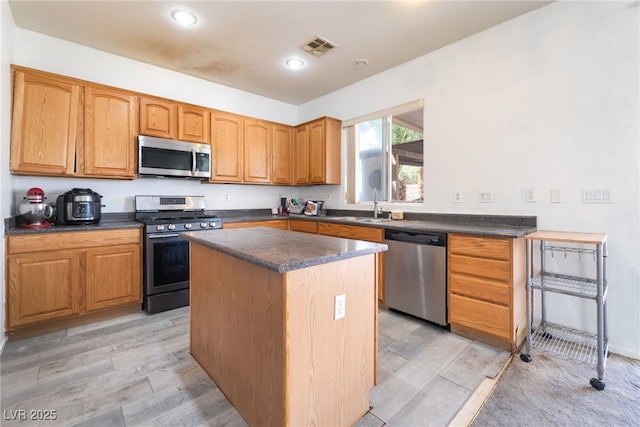 4062 W El Campo Grande Ave, North Las Vegas, NV 89031 - kitchen with stainless steel appliances, dark countertops, a center island, light wood-type flooring, and recessed lighting