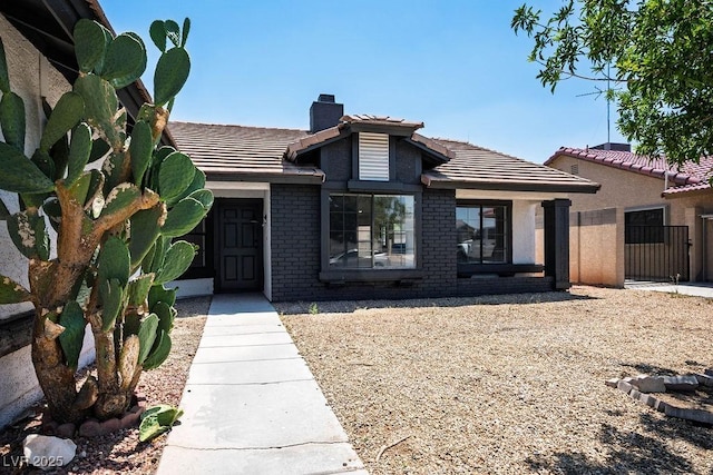 4319 Basil Leaf Ave, North Las Vegas, NV 89031 - view of front facade featuring a chimney, a tile roof, and brick siding
