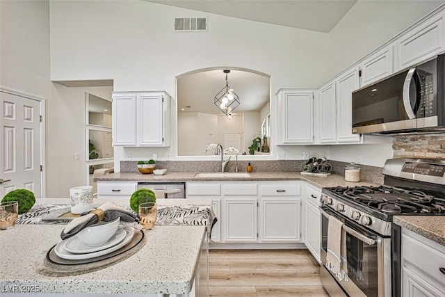 920 Siena Hills Ln, Las Vegas, NV 89144 - kitchen featuring stainless steel appliances, white cabinetry, light wood-style floors, and decorative light fixtures