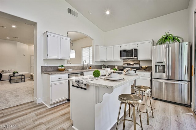 920 Siena Hills Ln, Las Vegas, NV 89144 - kitchen featuring appliances with stainless steel finishes, white cabinetry, high vaulted ceiling, light wood-style floors, and a kitchen island