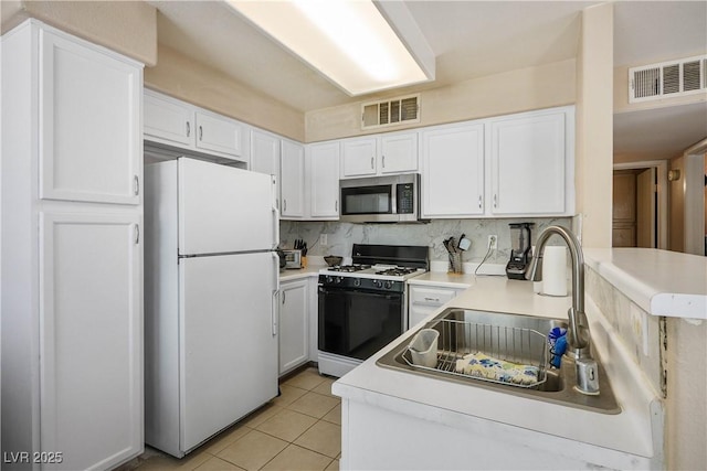 3042 Tarpon Dr Unit 202, Las Vegas, NV 89120 - kitchen featuring freestanding refrigerator, stainless steel microwave, gas range, white cabinets, and light tile patterned floors