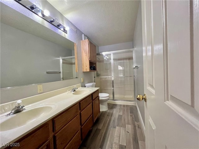 2627 S Durango Dr Unit 202, Las Vegas, NV 89117 - bathroom featuring a textured ceiling, a stall shower, wood finished floors, and double vanity