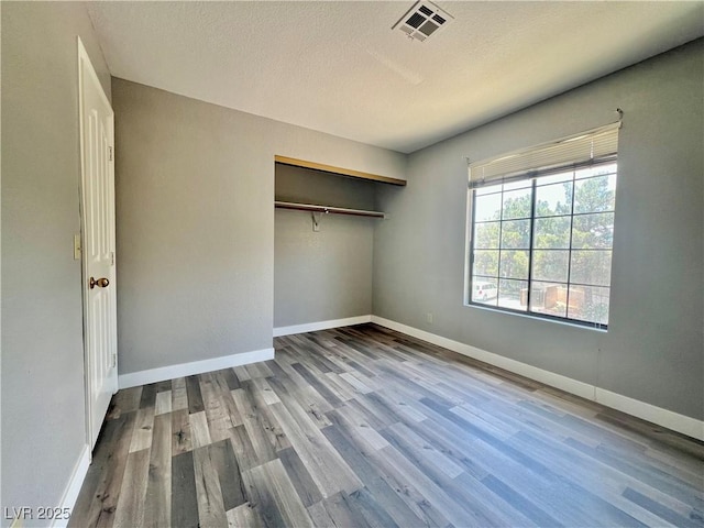 2627 S Durango Dr Unit 202, Las Vegas, NV 89117 - unfurnished bedroom featuring wood finished floors, a textured ceiling, and a closet