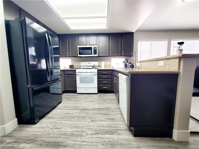 5104 Brookmere Dr, Las Vegas, NV 89130 - kitchen with white appliances, a peninsula, light wood-style floors, and light stone counters