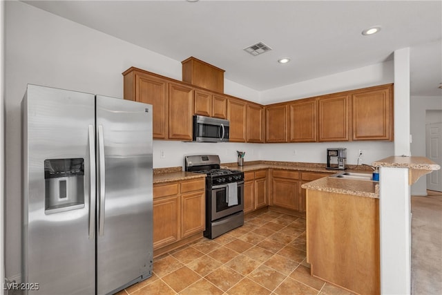 9269 Moonlight Nest Ln, Las Vegas, NV 89178 - kitchen with appliances with stainless steel finishes, a peninsula, recessed lighting, brown cabinets, and a breakfast bar
