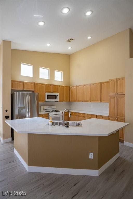9710 Geiger Peak Ct, Las Vegas, NV 89148 - kitchen with white appliances, a large island, light wood-type flooring, light countertops, and a high ceiling