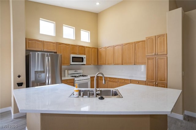 9710 Geiger Peak Ct, Las Vegas, NV 89148 - kitchen with white appliances, a high ceiling, a center island with sink, light countertops, and light wood-type flooring