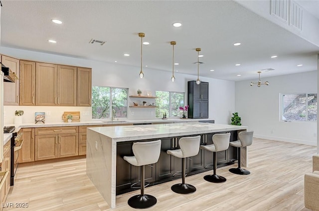 85 Alerion St, Las Vegas, NV 89138 - kitchen featuring recessed lighting, a center island, light stone counters, light wood finished floors, and a breakfast bar