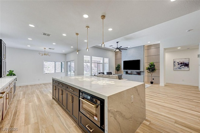 85 Alerion St, Las Vegas, NV 89138 - kitchen with light wood-type flooring, built in microwave, a ceiling fan, light stone counters, and a center island