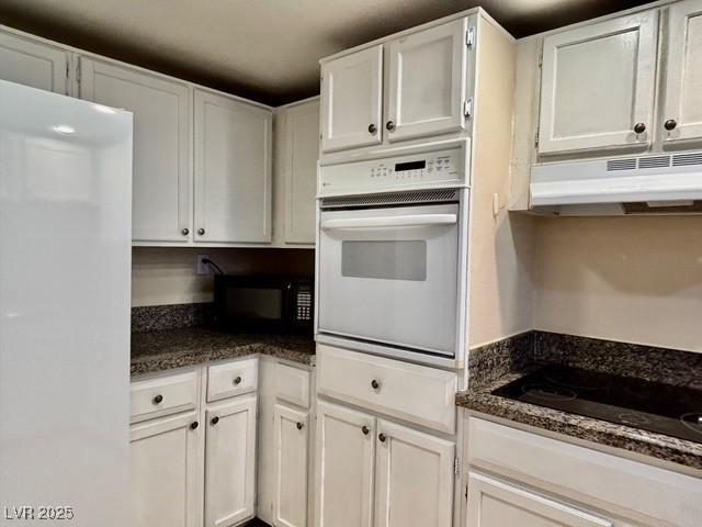 750 S Royal Crest Cir Unit 325, Las Vegas, NV 89169 - kitchen with black appliances, under cabinet range hood, white cabinetry, and dark stone countertops