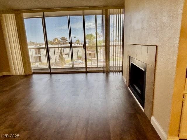 750 S Royal Crest Cir Unit 325, Las Vegas, NV 89169 - unfurnished living room with a wall of windows, dark wood finished floors, and a fireplace