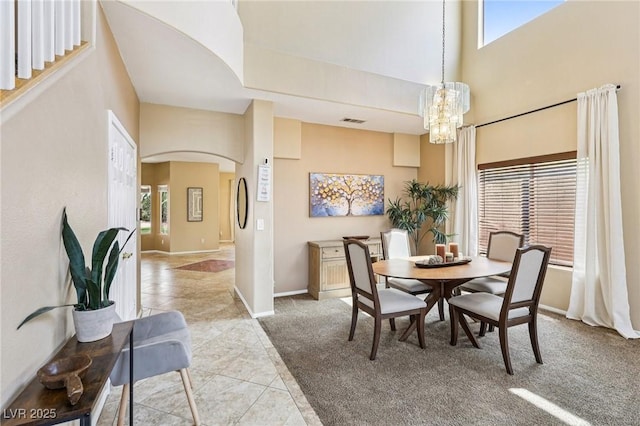 5434 Lost Ln, Las Vegas, NV 89118 - dining room featuring a high ceiling, a chandelier, light carpet, arched walkways, and light tile patterned flooring