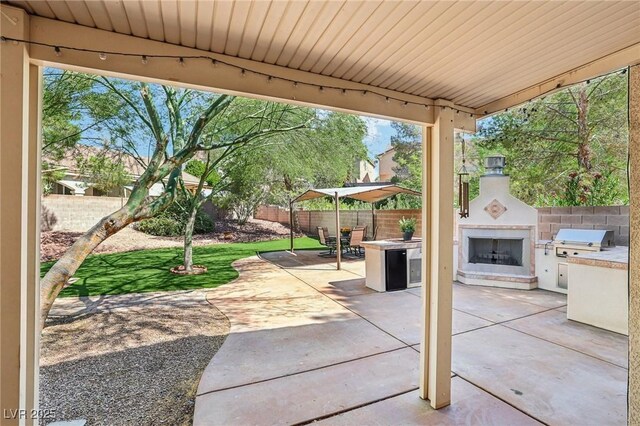 5434 Lost Ln, Las Vegas, NV 89118 - fenced backyard featuring a patio area, an outdoor fireplace, and exterior kitchen