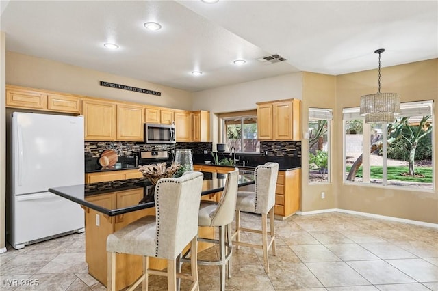 5434 Lost Ln, Las Vegas, NV 89118 - kitchen featuring appliances with stainless steel finishes, light brown cabinets, dark countertops, backsplash, and a breakfast bar